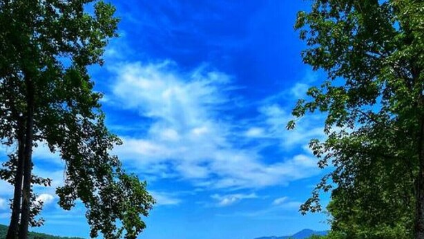 A hot tub on a wooden deck with a scenic mountain view. - Smokey Mountain Retreat (Waynesville)