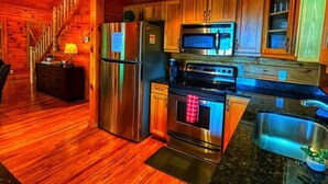 A kitchen with wooden cabinets, stainless steel appliances, and a granite countertop. - Smokey Mountain Retreat (Waynesville)
