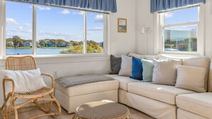 Una habitación acogedora con una silla de mimbre, un sofá blanco y vistas a un lago.