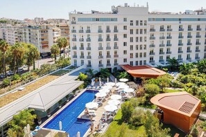 Un hôtel doté d’une piscine, d’un espace de détente extérieur et d’un grand bâtiment à plusieurs étages.