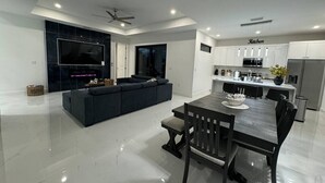 Eine moderne Küche mit Essbereich, ein großes, dunkel gefärbtes Sofa und ein Deckenventilator.