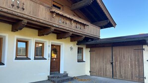 Une maison traditionnelle en bois, avec une porte d’entrée, trois fenêtres et une porte de garage.