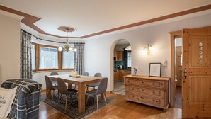 Un coin repas avec une table et des chaises en bois, un tapis et un canapé à carreaux.