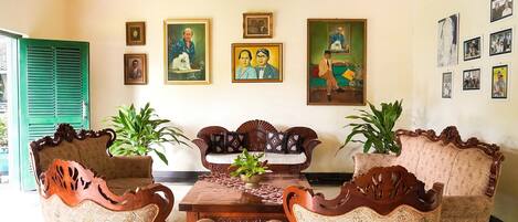 A traditional room with two ornate wooden sofas, a wooden coffee table, and a green door.