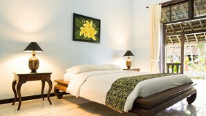 A bedroom with a bed, two bedside tables with lamps, a large window with curtains, and a wall-mounted picture of a flower. - Margo Utomo Eco Resort (Kalibaru)