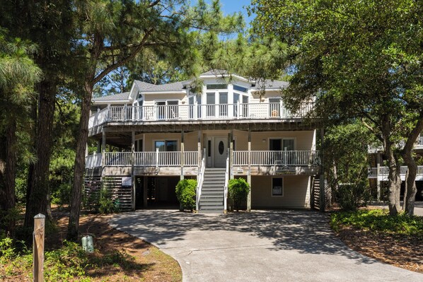 A two-story building with a balcony, a front door, and a driveway.