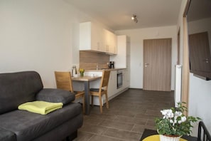 A modern kitchen with white cabinets, a dining table, and a sofa.