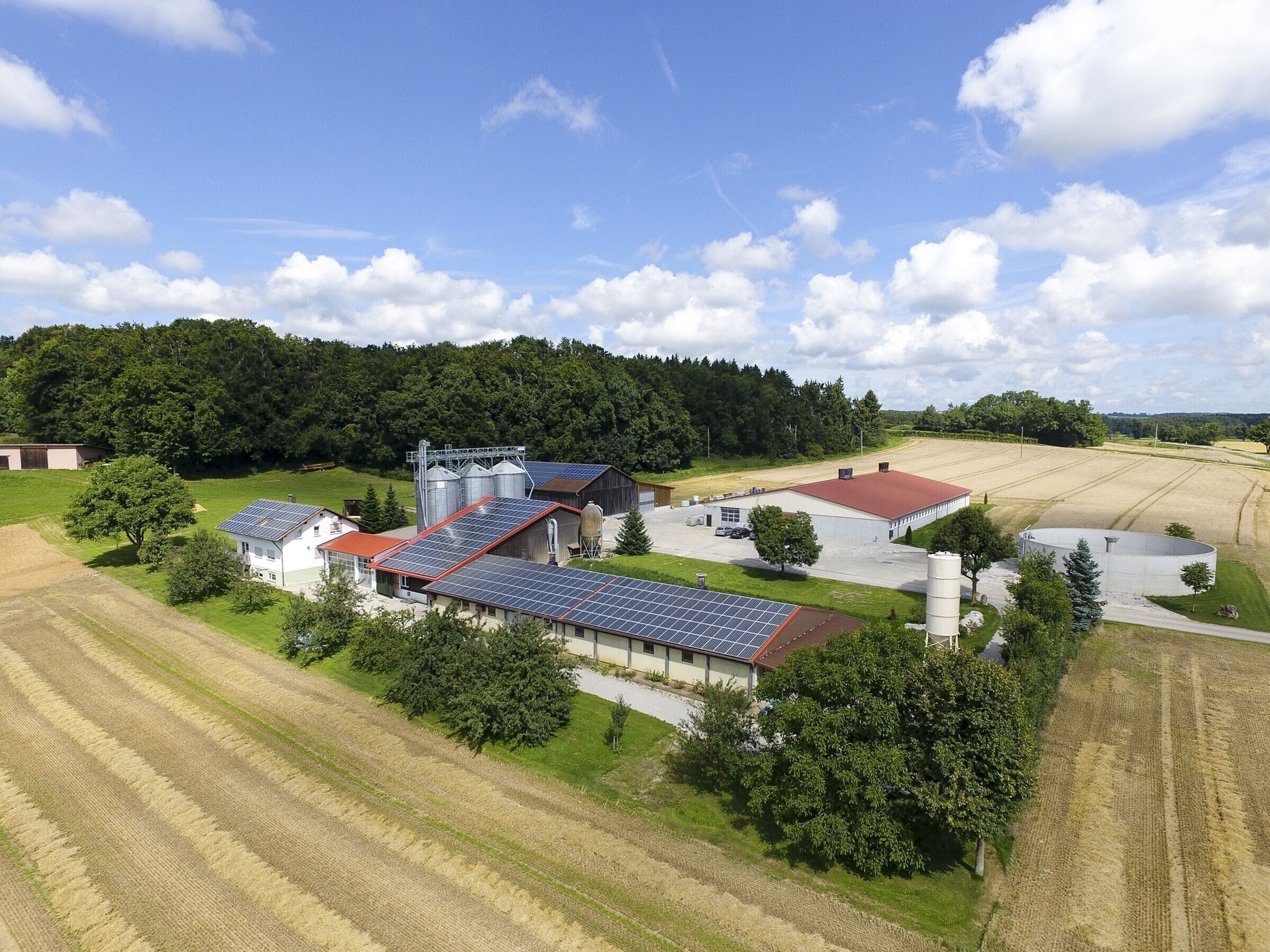 Una granja con paneles solares, graneros y campos.