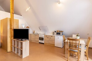 Et moderne køkken med træskabe, indbygget ovn, mikroovn og et spiseområde med bord og stole.