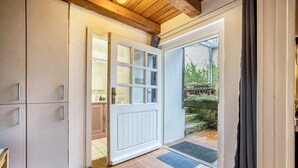 A room with a white door, a tiled floor, and a view of a garden outside. - Holiday Apartment 'Alte Polsterei' with Private Terrace, Shared Garden and Wi-Fi (Nienstädt)