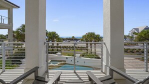 Un balcon avec vue sur une piscine et l’océan.