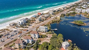 Vue aérienne d’une ville côtière avec une plage, des maisons et une étendue d’eau couverte de nénuphars.