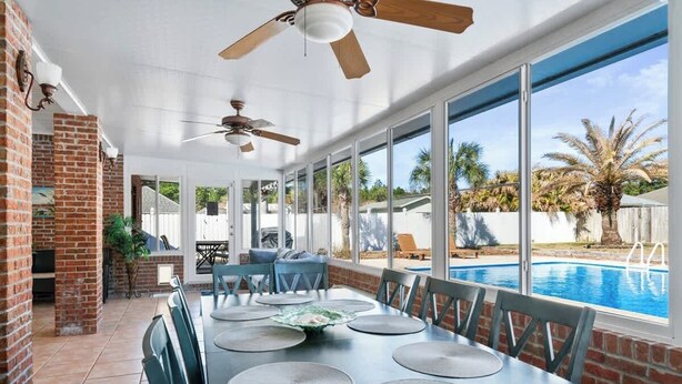 A covered patio with a pool view, brick walls, and ceiling fans.