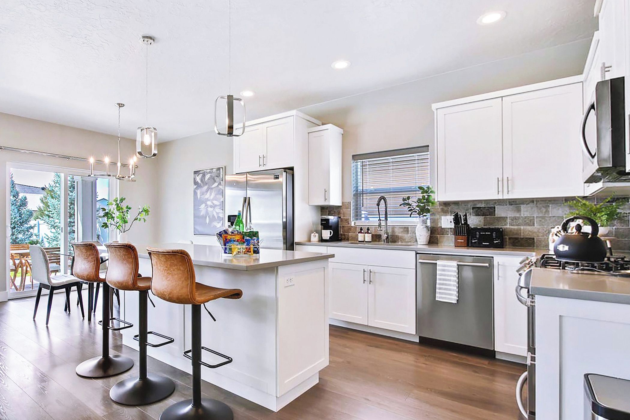 A modern kitchen with white cabinets, stainless steel appliances, and a central island with bar stools.