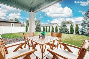An outdoor patio with a wooden table and chairs, surrounded by a white fence and a lawn. - Top Rated • Spotless & Spacious • Near Top Dining, Shopping & Entertainment (Meridian)