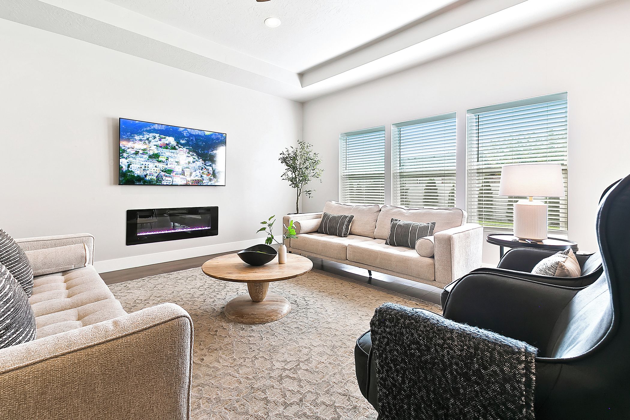 Una sala de estar moderna con un sofá, sillones, una mesa de centro y un televisor montado en la pared.