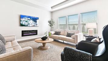 Una sala de estar moderna con un sofá, sillones, una mesa de centro y un televisor montado en la pared.