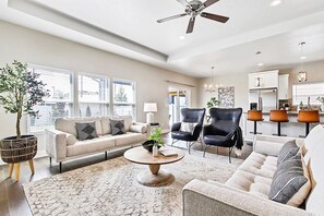 A modern living room with a sofa, chairs, a coffee table, and a ceiling fan. - Top Rated • Spotless & Spacious • Near Top Dining, Shopping & Entertainment (Meridian)