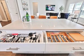 A modern kitchen with a large island, white cabinetry, and a variety of kitchen tools and utensils. - Top Rated • Spotless & Spacious • Near Top Dining, Shopping & Entertainment (Meridian)