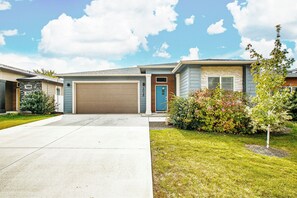 A residential house with a garage, a front yard with grass and shrubs, and a clear sky. - Top Rated • Spotless & Spacious • Near Top Dining, Shopping & Entertainment (Meridian)