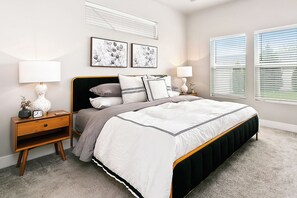A bedroom with a bed, nightstands, lamps, and artwork on the walls.