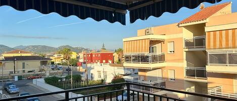 Un balcón con vistas a una zona residencial, con edificios y coches aparcados.