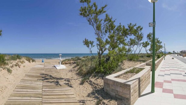 A wooden boardwalk leading to a beach with pine trees on either side. - Anacasa Macomer Oliva Playa AP803 (Oliva)