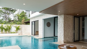 Un espace piscine moderne avec un mur en pierre, un plafond en bois et une vue sur la verdure environnante.