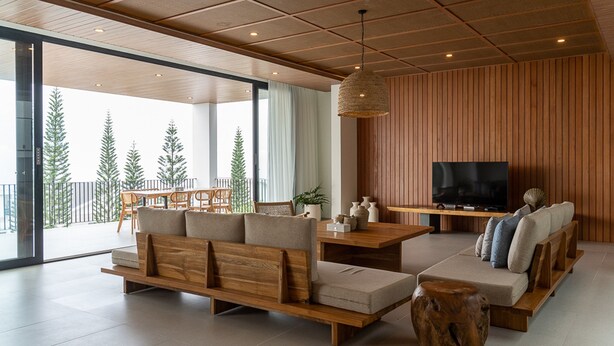 Un salon moderne avec un canapé en bois, un téléviseur et un coin repas comprenant une table et des chaises.