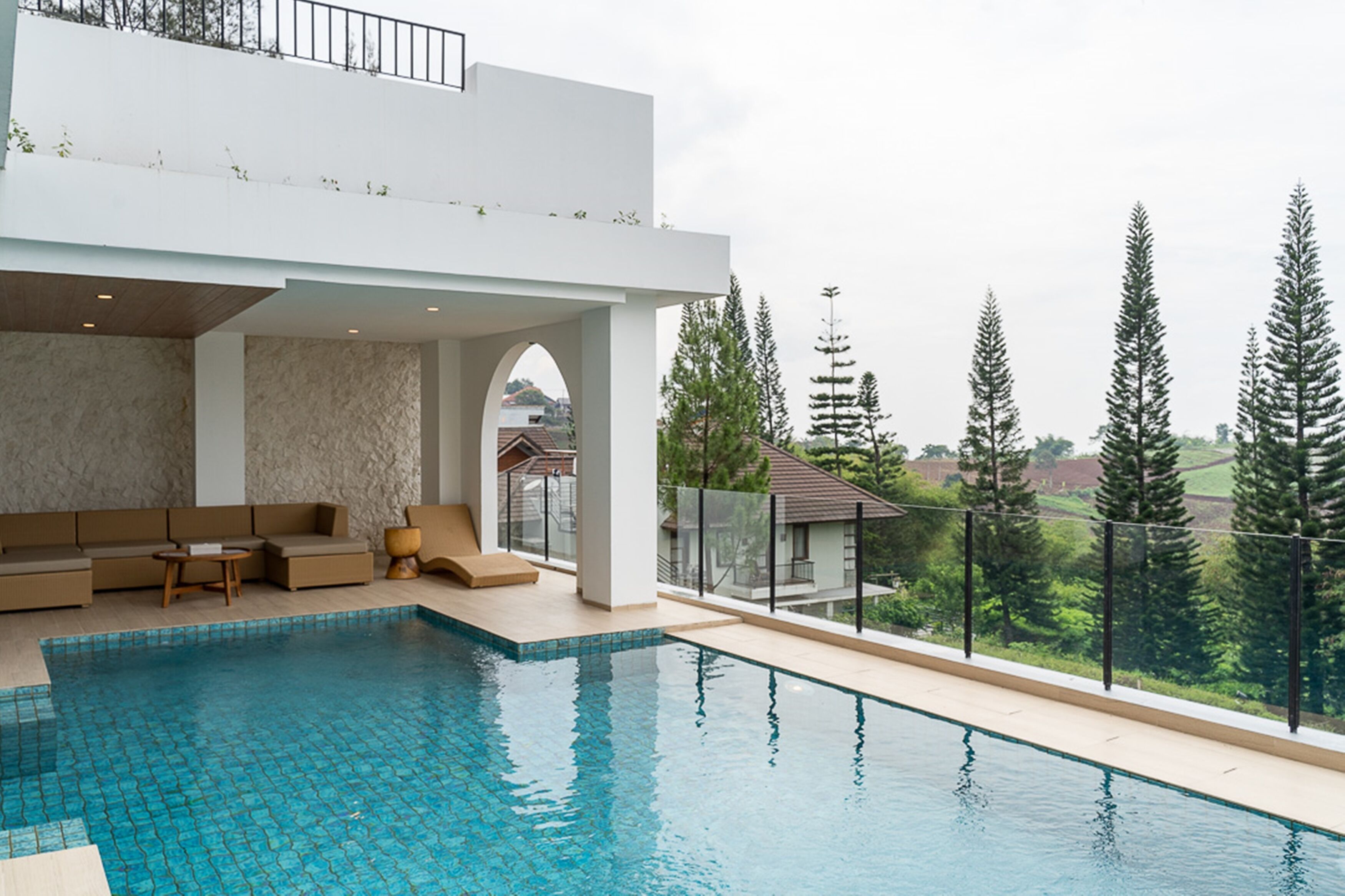 Un área de piscina moderna al aire libre con zona de estar y vistas del paisaje circundante.