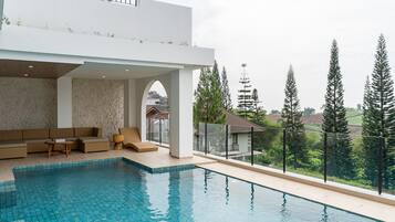 Un área de piscina moderna al aire libre con zona de estar y vistas del paisaje circundante.