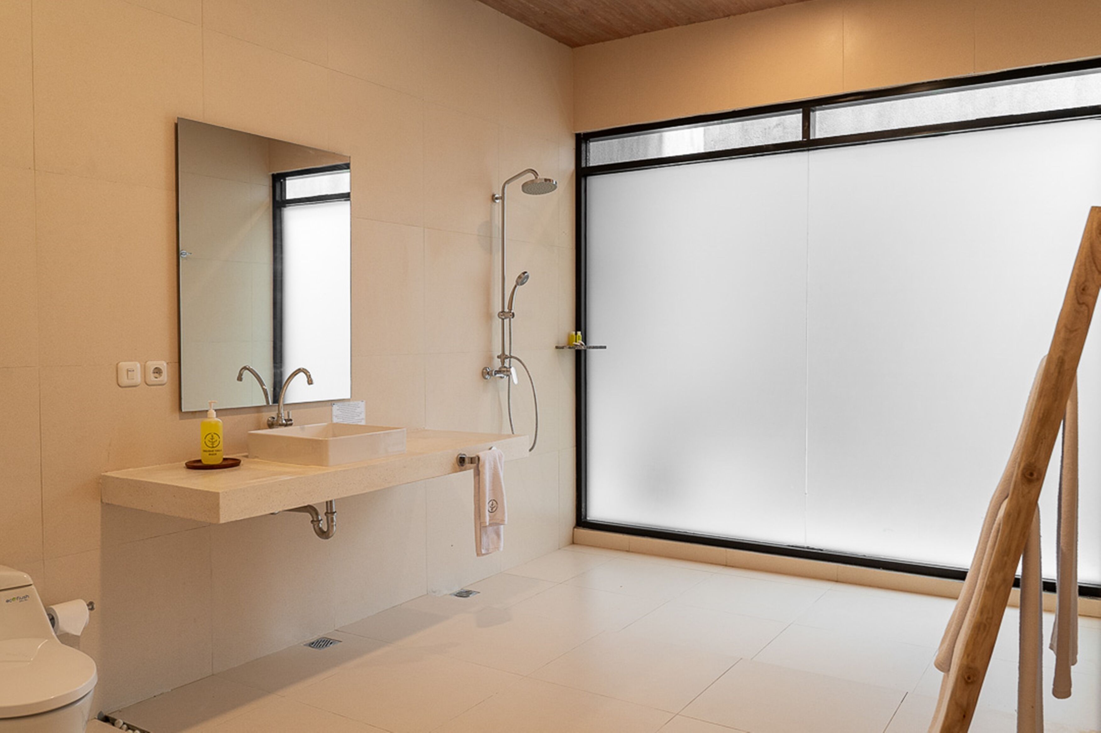 A modern bathroom with a large mirror, a sink, a shower, and a toilet.