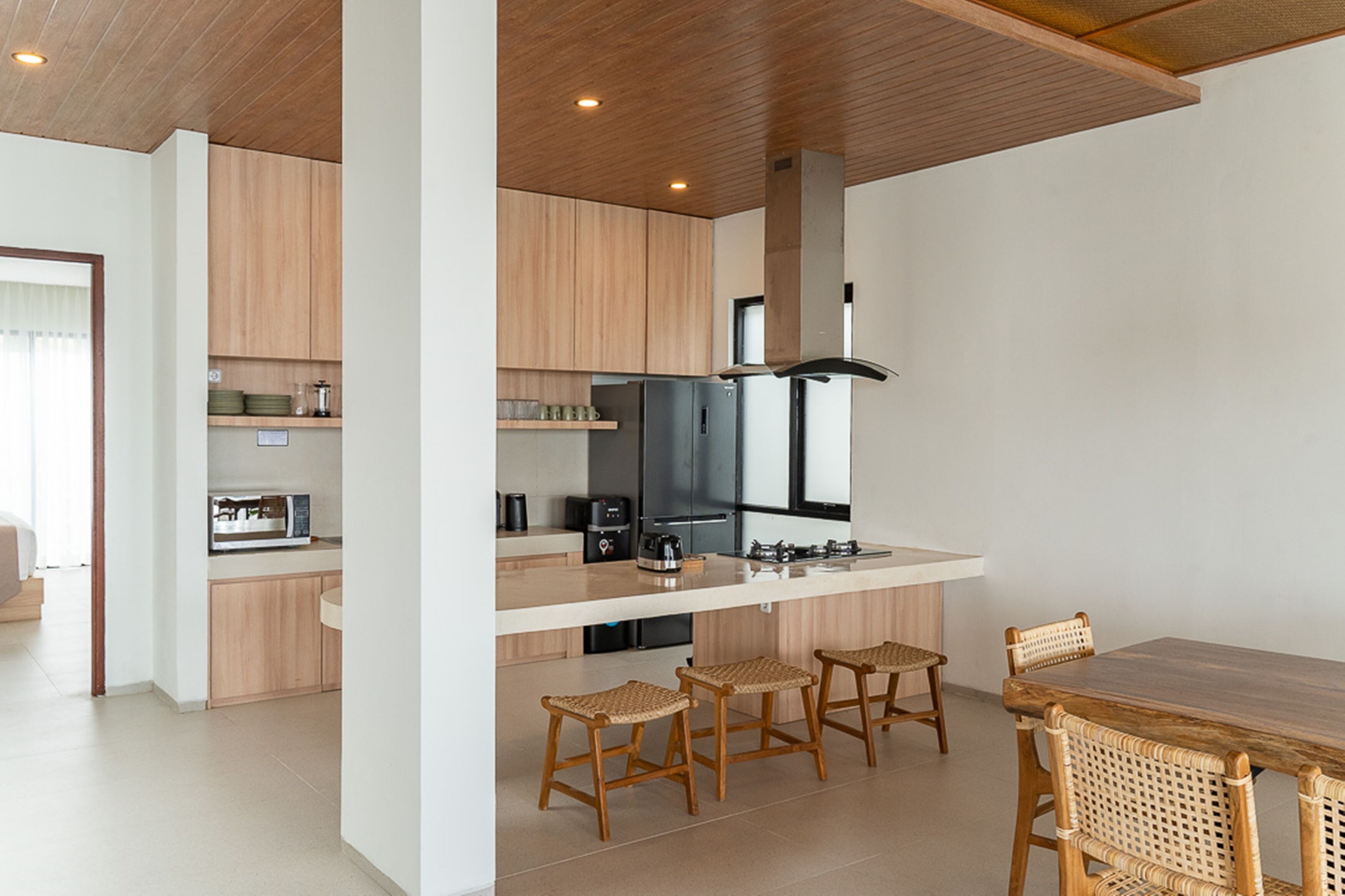 Une cuisine moderne avec des meubles en bois, un îlot central doté de tabourets et une table à manger avec des chaises.
