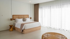 Une chambre à coucher moderne avec un lit en bois, une petite table de chevet et une grande fenêtre ornée de rideaux légers.