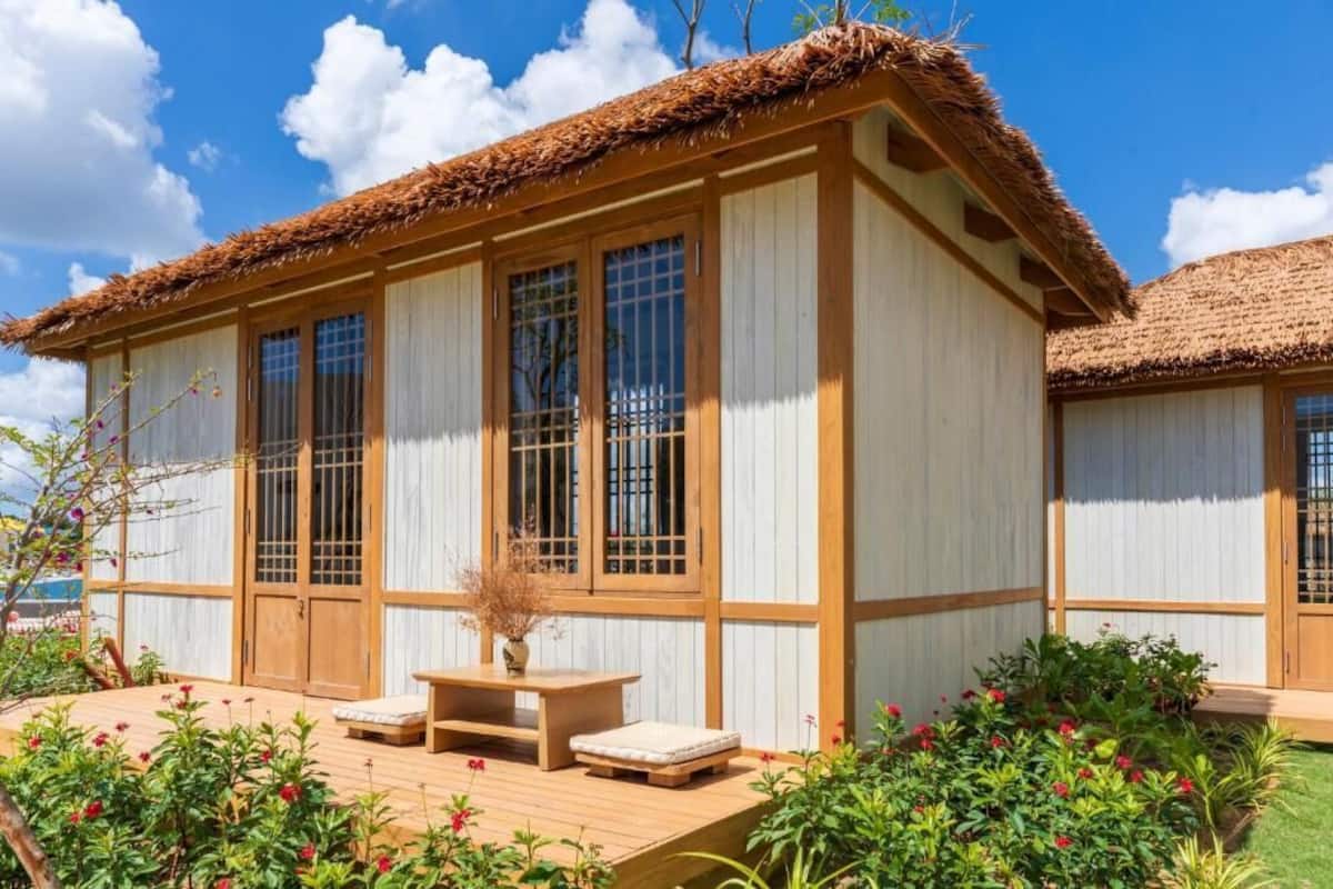 A traditional wooden building with a thatched roof, large windows, and a wooden deck with seating.