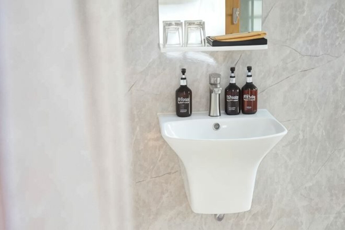 A bathroom with a white sink, two bottles of hand soap, and a mirror above the sink.
