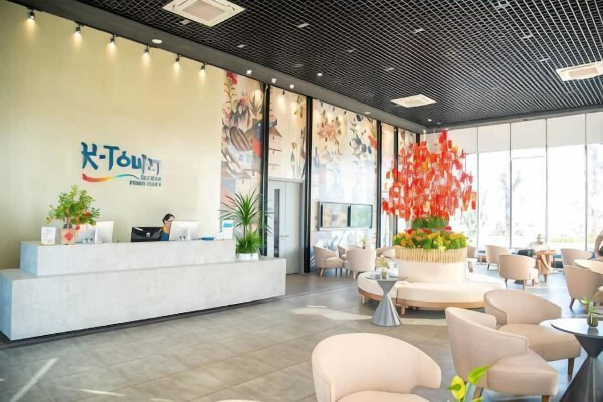 A hotel reception area with a reception desk, seating area, and large windows.
