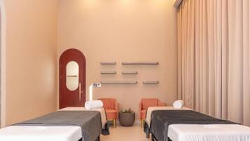 A modern hotel room with two beds, a small round table, and a mirror on the wall.