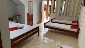 A room with two wooden beds, a small round table, and a door leading outside. - Suite Pousada Paraío (Guarapari)