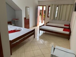 Quarto com duas camas de madeira, uma mesinha redonda e uma porta que dá para o exterior.
