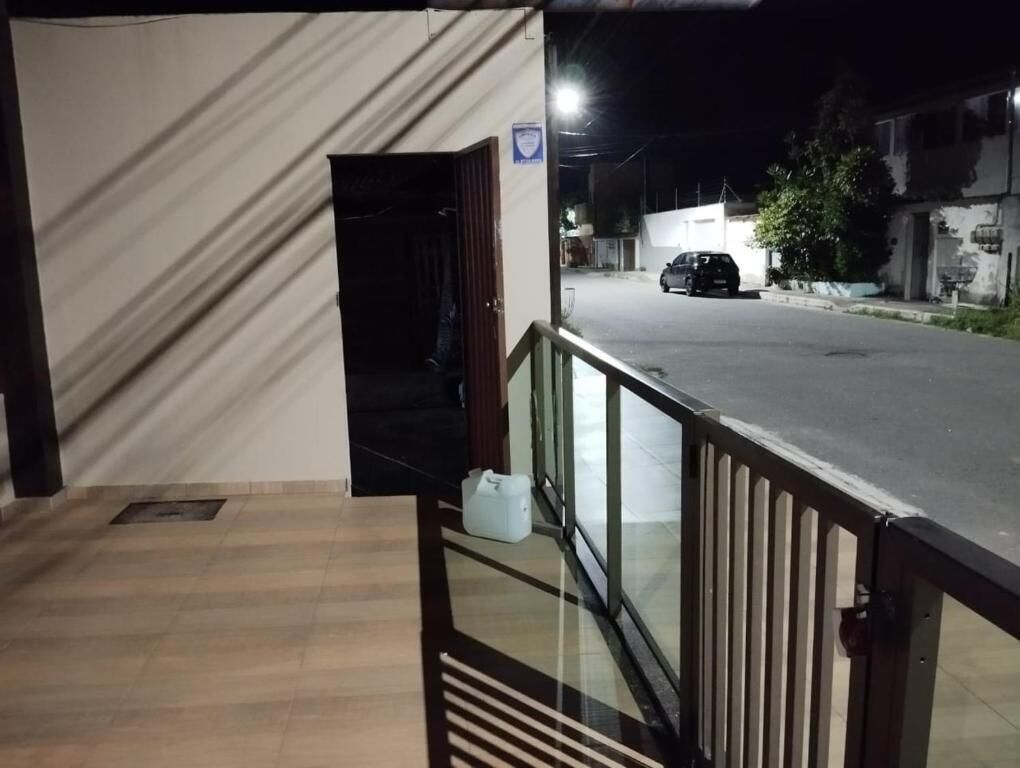 Entrada de hotel com piso de madeira, porta de vidro e vista para a rua com carros estacionados.
