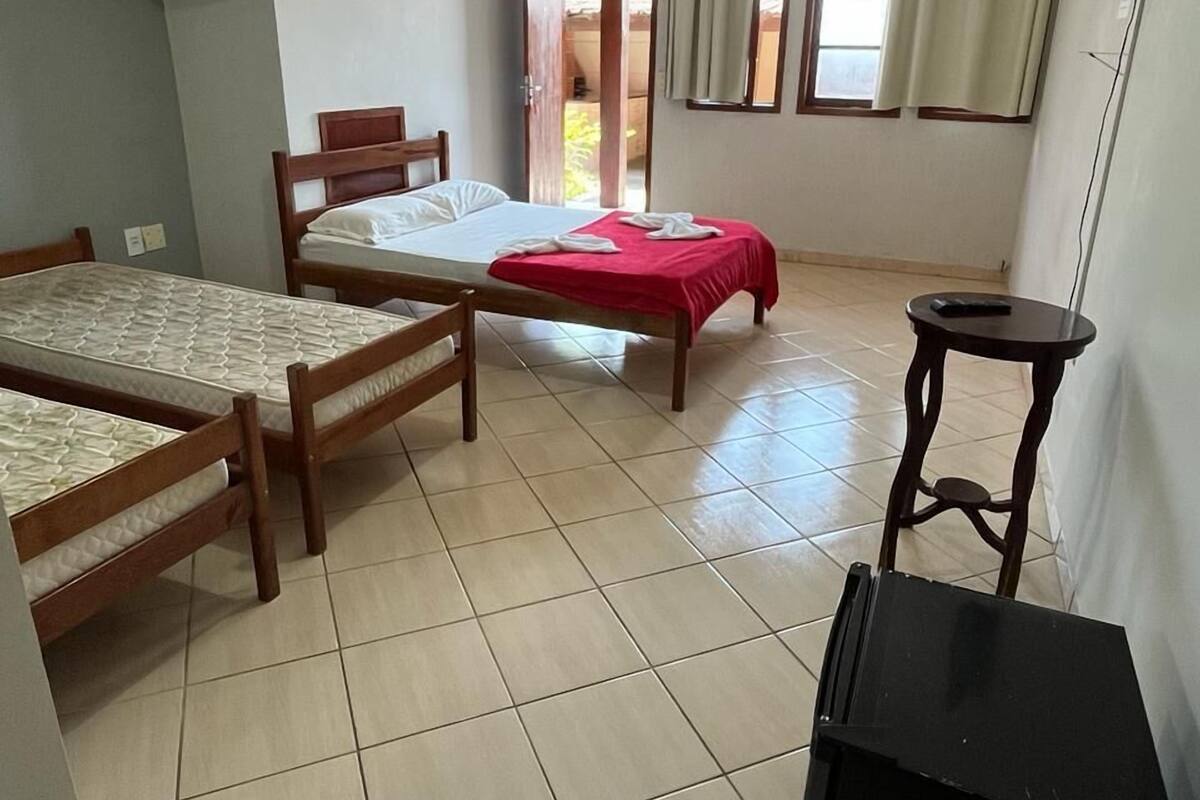 A room with two single beds, a small table, a TV, and a door leading to an outdoor area.
