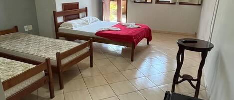 Una habitación con dos camas individuales, una mesita, un televisor y una puerta que da a un espacio al aire libre.