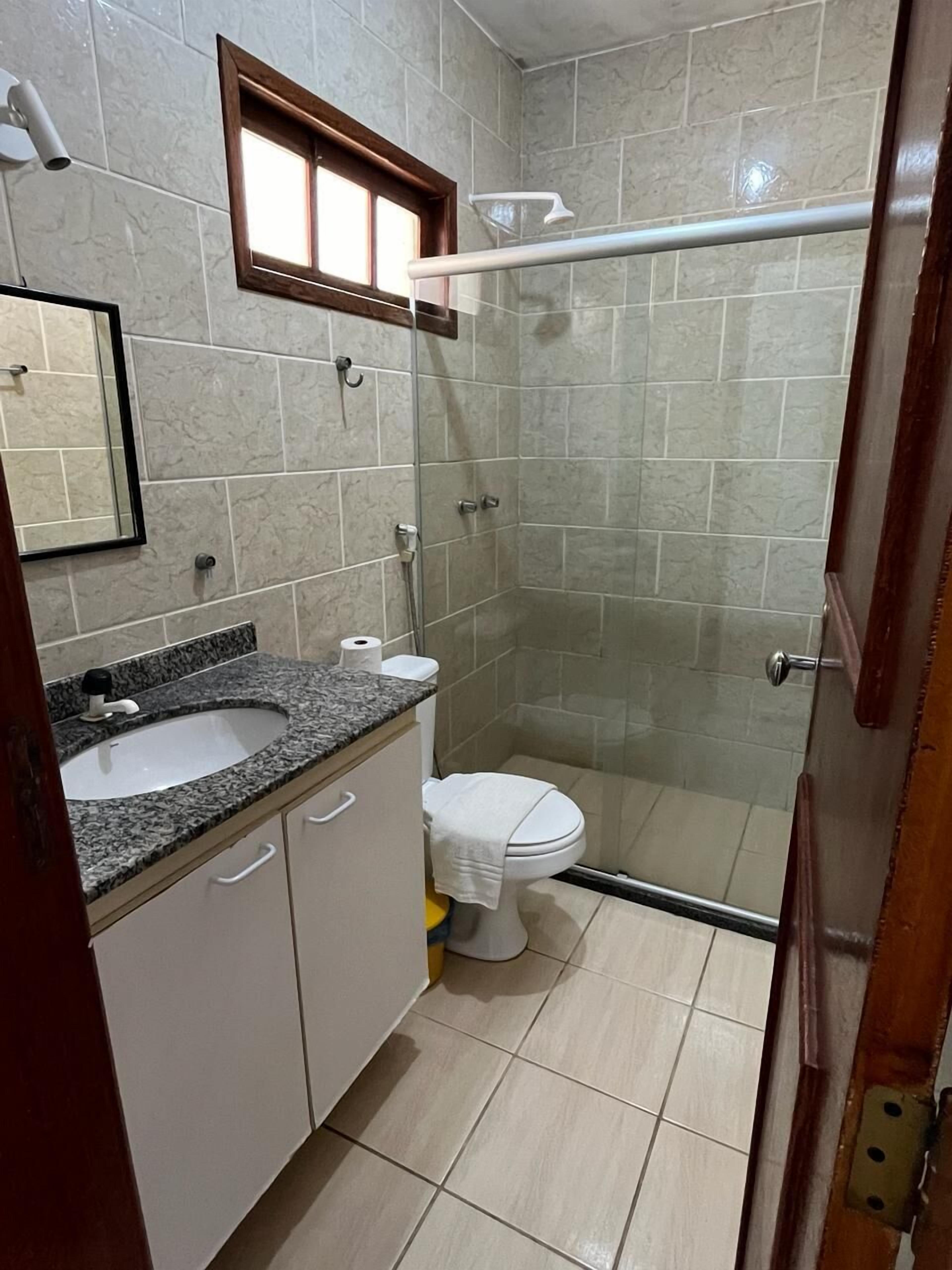 Une salle de bain comprenant un lavabo, des toilettes et un espace douche.