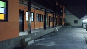 A building with a covered walkway and multiple doors, likely a hotel or hostel. - Suite Pousada Paraío (Guarapari)