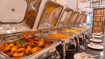 En buffet med flere forskellige retter, heriblandt stegt kylling og ris.