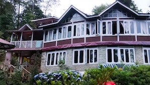 A two-story house with a balcony, large windows, and a stone facade.