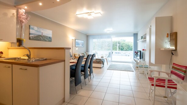 Cocina moderna con comedor, sala de estar con sofá y vistas al exterior.