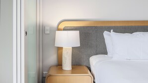 A neatly made bed with white linens, a wooden headboard, and a bedside table with a lamp. - The Sand Resort Kingscliff - Studio Apt (Tweed)