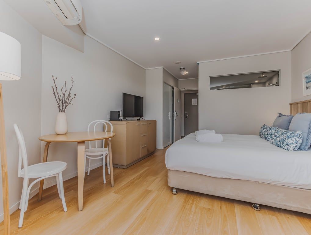A modern hotel room with a bed, a desk, and a chair.